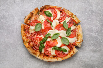 Delicious Caprese pizza with tomatoes, mozzarella and basil on light grey table, top view