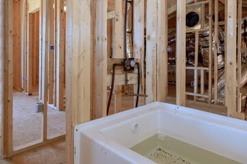 Under construction house featuring new acrylic bathtub between beams frame in a bathroom