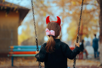 Naughty Disobedient Little Child Wearing Devil Horns Playing Alone. Misbehaving toddler girl...