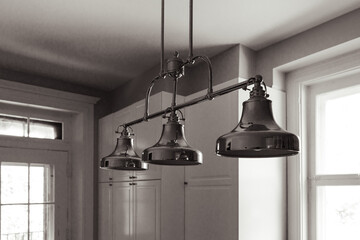 luminaire d'une cuisine blanche à trois ampoules éteintes chromé accroché au plafond avec la...