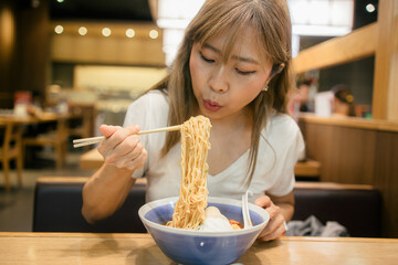 Asian women enjoy eating ramen noodles in japanese restaurant