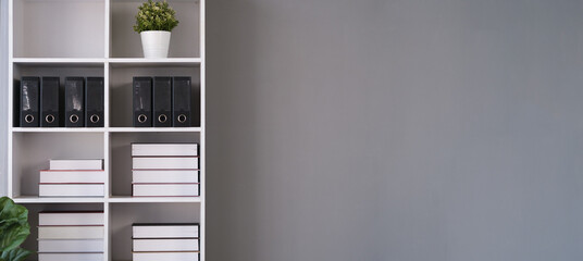 White bookshelf and poster on white wall on gray wall. Copy space for your text. © wattana