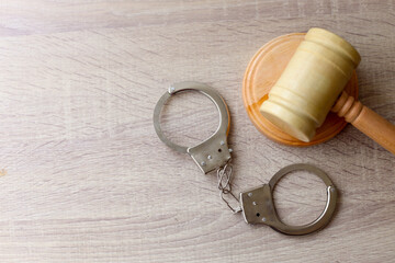Wooden gavel and handcuffs on the table with copy space on left side. Legal law concept. Top view,...