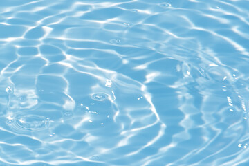 Blue water with ripples on the surface. Defocus blurred transparent blue colored clear calm water surface texture with splashes and bubbles. Water waves with shining pattern texture background.