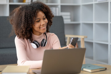 An American woman sits in her living room on weekends, she spends the holidays at her home and spends her time surfing social media and watching movies and listening to music in a fun and relaxing way