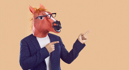 Man wearing business suit, funny silly animal masquerade horse mask and eyeglasses standing...