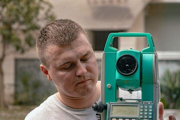 A surveyor worker takes measurements in the field using a theodolite total station. Portrait of a...