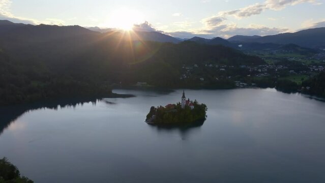 Drone video from Bled Slovenia. A beautifull glaciar lake with a beautifull island in the middle of the lake with sourouding mountains and nature. Filmed at sunset at golden hour.