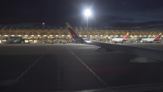 Madrid airport night view from a plane window T4 terminal and plane wing visible during blue hour runaway