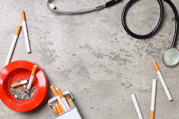 A pack of cigarette with red ashtray and stethoscope on gray background with copy Space. Quit...