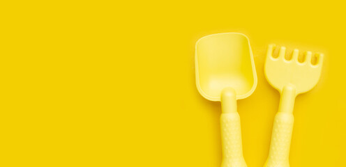 Plastic toys, shovels on yellow background. Summer background concept
