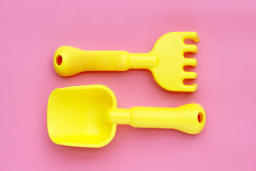 Plastic toys, shovels on pink background. Summer background concept