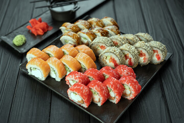 Sushi set with salmon, eel and tuna on a black plate, assorted sushi rolls on a dark background, japanese food