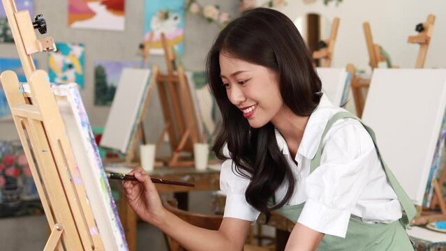 Asian woman painting on canvas, she is an artist who creates watercolor painting, art painting. Concept artist design drawing art on canvas paper.