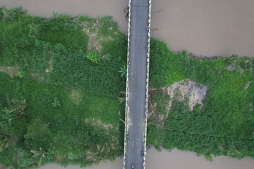 Aerial view of the long bridge over the brown watery river. the river delta is overgrown with green...