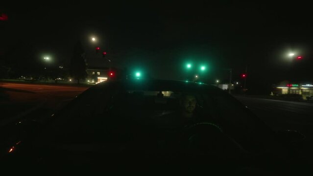 Dangerous male caucasian killer driving in the night and escaping and taking turns. Dramatic, moody with a red tint. Windshield POV Wide Shot. American streets.