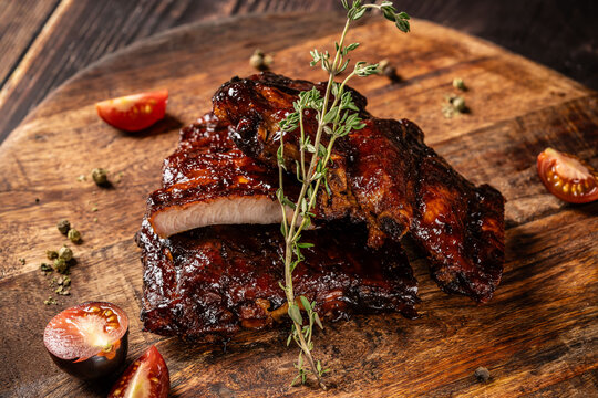 American cuisine, glazed fried ribs in honey and soy sauce lie on a wooden board. background image for the menu.