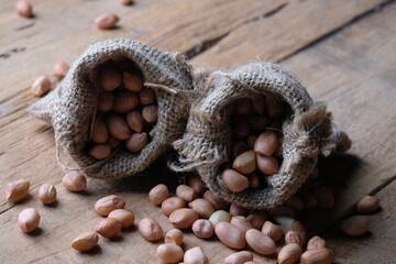 raw peanuts in burlap gunny sack. Peanut is a leguminous plant belonging to the Fabaceae tribe that is cultivated. Arachis hypogaea. vegetable protein, calcium, magnesium, iron. kacang tanah mentah.  - obrazy, fototapety, plakaty