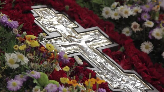 Orthodox cross lies on the altar in flowers. Silver Orthodox cross on the altar in the church