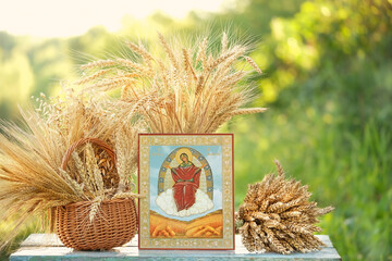 old orthodox icon with Our Lady image and ripe grain ears on table in garden, natural background. ritual prayer for Icon of the Most Holy Theotokos, helper of the harvest. 