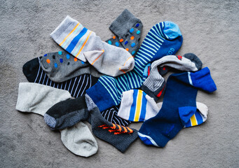 Overhead shot of a pile of mismatched odd socks on gray carpet.