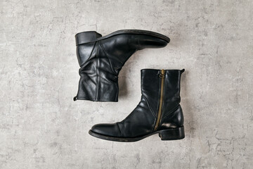 Black leather side zip boot on a concrete.