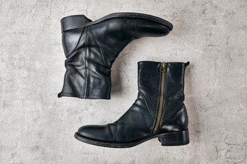 Black leather side zip boot on a concrete.