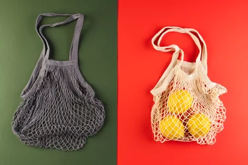 Poster Brown and white mesh net bags with lemons and copy space on red and dark green background © vectorfusionart