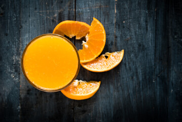 glass of fresh orange juice with fresh fruits on dark wooden table, high Vitamin C, orange drink