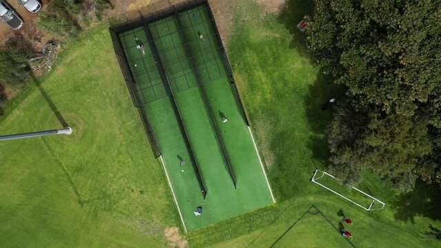 Cricket training outdoor structure with cricketers practicing at Perth city park. Aerial top down circling