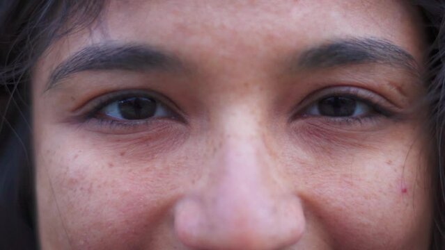 Macro shot of Indian Woman eyes looking at camera.  Eyes of confident young woman with freckles on face and healthy skin. Close-up of eyes of smiling girl, happy people