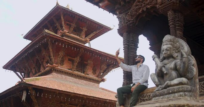A man showing famous Patan Durbar Square Heritage of Nepal in a video call sitting and appreciating the architectural beauty. Tourism place in Nepal and Natural heritage beauty 4K