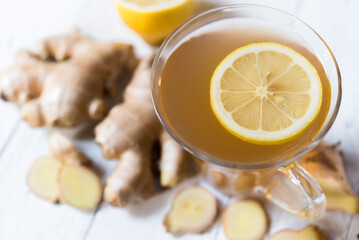 Ginger tea and fresh ginger root on white wooden background