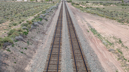 Railroad track in countryside crossing USA Arizona desert with low vegetation background. Above view