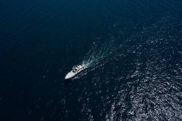 Large white yacht on the water in motion top view. Luxury motor boat on dark blue water aerial...