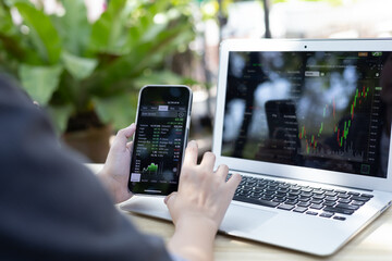 Business woman look at the phone screen shows the stock digital graph. Stock exchange market graph...