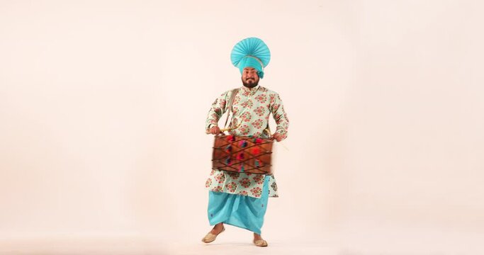 Sikh man doing bhangra dance with drum during Baisakhi celebration