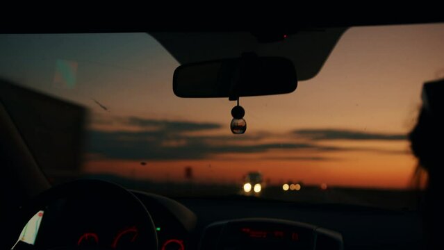 Blurred headlights of column of cars on highway from automobile window at sunset