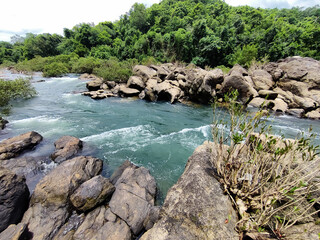 Mesmerising wild lake view , flowing water surrounded by rocks under the cloudy sky , from Bedoor Forest Lake Kerala