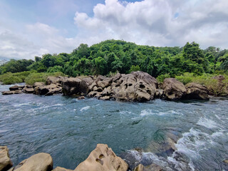 Mesmerising wild lake view , flowing water surrounded by rocks under the cloudy sky , from Bedoor Forest Lake Kerala