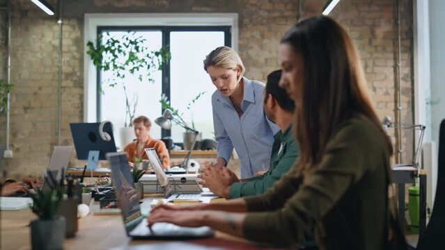Woman mentor help intern man sitting coworking. Coach explaining work to trainee