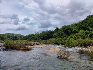 Mesmerising wild lake view , flowing water surrounded by rocks under the cloudy sky , from Bedoor Forest Lake Kerala