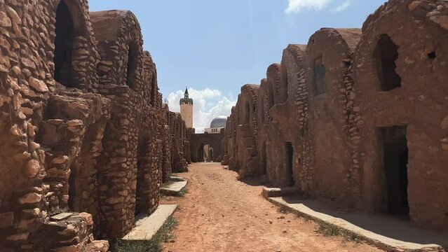 Walking through ruins of Ksar Hadada village in Tunisia with mosque in background