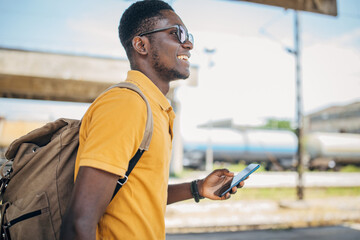 Young man with headphones and mobile phone on the train station