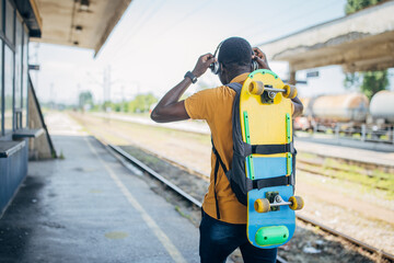 Young man with skateboard waiting for train