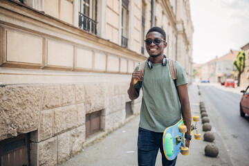 Young man with skateboard walking in the city