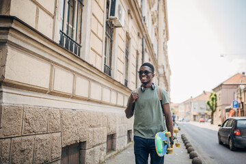 Young man with skateboard walking in the city
