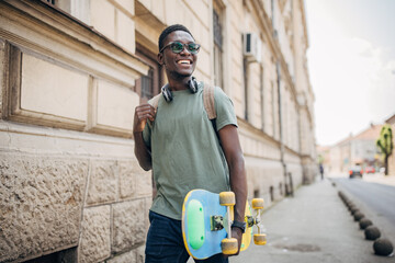 Young man with skateboard walking in the city - Powered by Adobe