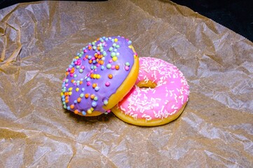 Pink and purple sweet donuts with icing and sugar decoration. Object concept. Side view. Lying flat. Food concept. Macro concept. Sugar is bad for health