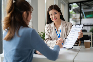 A gorgeous Asian businesswoman is having a meeting with a female client to sign a contract.